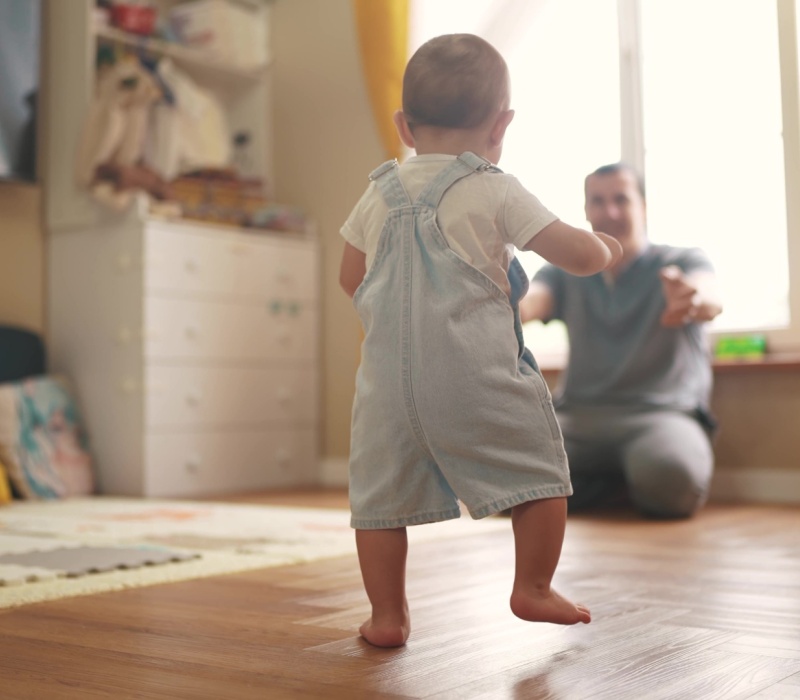 A toddler walking towards a parent.