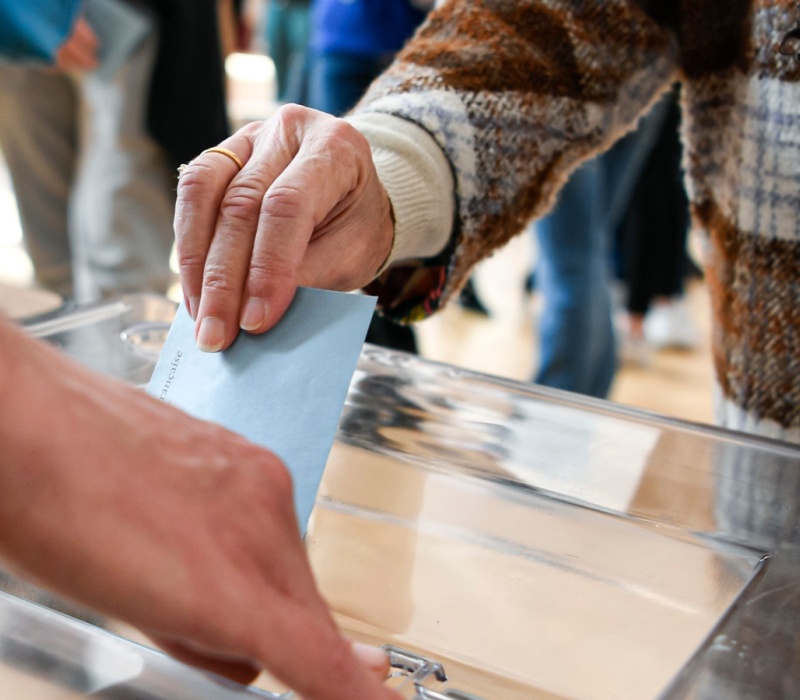 A person putting a ballot paper into a box.