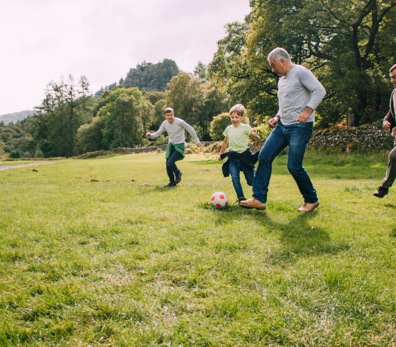 Multi-generational family playing football in a park.