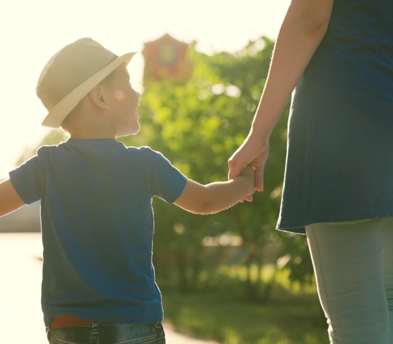 A family with a young child holding hands outdoors.