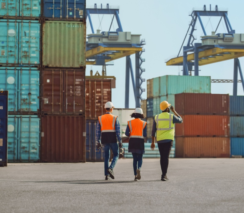 Workers walking through a shipping cargo container terminal depot.