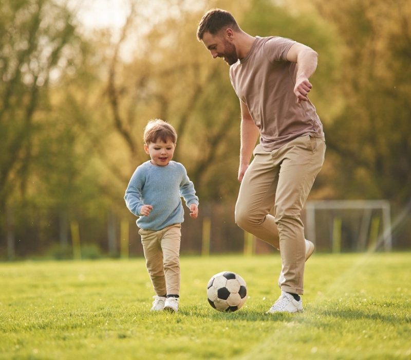 A father playing football with his young son.