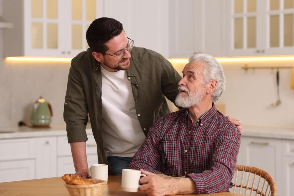 A father and son talking in a kitchen.